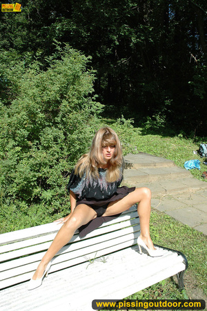 Pretty girl goes naughty pissing on white public bench close to forest - Picture 4