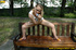 Young pretty blonde in glasses and short skirt sits on public bench to