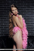 Curled hair girl adores to touch her body with pink feathers