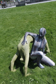 Two green and grey zentai wearing flexible chick stretching outdoor.