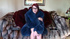 Red lady in glasses and a blue fur coat on a fur sofa
