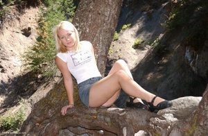 Slutty blonde teen posing in a jeans skirt topless on the tree - Picture 1