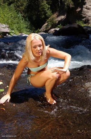 Blonde teen babe takes off her bikini to pose nude a the mountain river - Picture 3