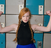 Red cutie in a black top and blue skirt posing for you