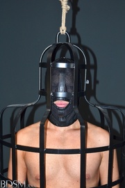 Ebony mistress in a cop's cosplay dominating masked dude in a special cage