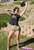 Lovely trick in a black shirt and green shorts plays with a hose outdoors.