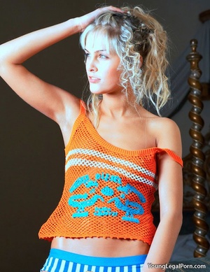 Curly-haired blonde in an orange knitted top and striped blue panties stripping. - Picture 1