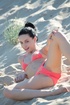 Cool brunette teen with a hair knot posing in a coral mini0bikini on the