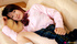 Doe in a pink blouse and a plaid skirt poses on a white sofa.