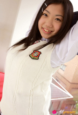 Wench poses in her sweater vest and school uniform on a red sofa. - Picture 3