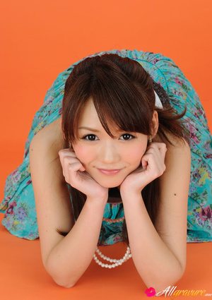 Minx in a flowery blue skirt and white top poses on an orange chair. - Picture 10