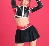 Pit babe in leather gear and boots posing in front of a red background.