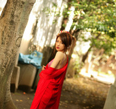 Harlot in a red robe and purple bikini poses under a tree.