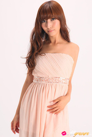 Vamp poses in her pink dress and wedges against a white background.