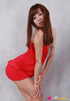 Female in a red dress and black heels poses against a grey background.