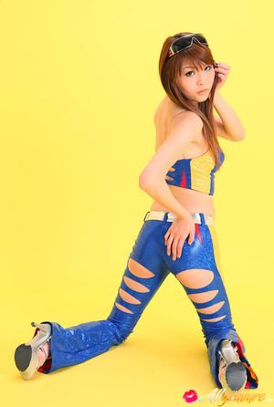 Pit diva in blue leather gear poses against a yellow background. - Picture 4