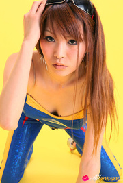 Pit diva in blue leather gear poses against a yellow background.