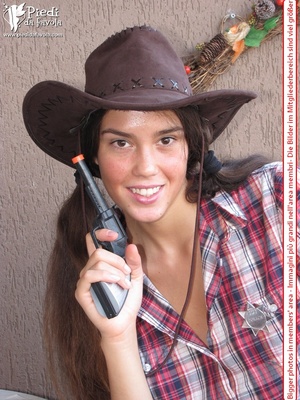 Little brunette pigtailed cowgirl wearing a hat, checked shirt and pantyhose looking dangerous with her gun - Picture 3
