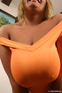 Smiling blondie in orange top and skirt shows and licks massive big tits