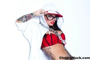 Hot tattooed hip hop wearing loose red and white jacket, jogging pants, cap and sneakers shows her sexy cleavage in black and red bra wearing glasses and chain necklace while she poses beside her boom box in a white room.