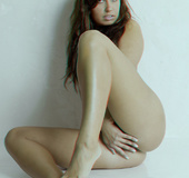 Elegant gurl in black heels poses naked against a white wall.