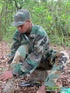 Gentleman in battle dress uniform lays down on fallen leaves to display