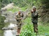 Two men in camo clothes chilling out by the river.