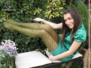 Young seductress in green dress, pantyhose and black shoes shows feet outdoors - Picture 10