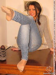 Cute chick in tight blue jeans drops shoes to display sweet cute feet on table