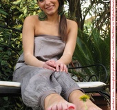 Alluring broad on a white bench showing off her red painted toe nails.