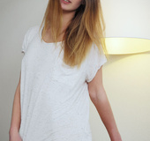 Alluring girlie in a white chemise opens her clam on a grey chair.