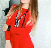 Elegant madam sheds her red dress in front of a purple couch.