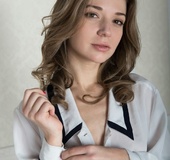 Desirable chiquita in a white blouse with black trim poses nude by the
