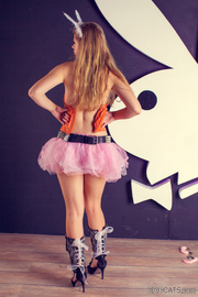 Lovely fair-haired teen in an range top, pink bouffant skirt and bunny ears undresses