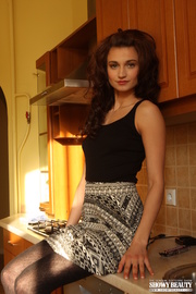Angelic floozy in a black top and patterned skirt gets naked in the kitchen.