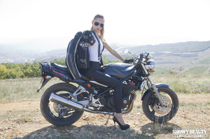 Biker chick in a leather jacket, white shirt and tight pants touches her twat on the bike. - Picture 1