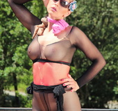 Woman leaning over a balcony has on black nylons with the ass cut out