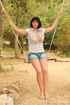 Girl in jean shorts on a makeshift swing shows off tits and shapely legs