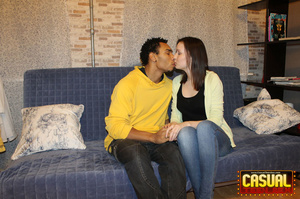 Captivating lass in a black shirt and jeans sits on a black dick on the blue sofa. - Picture 2