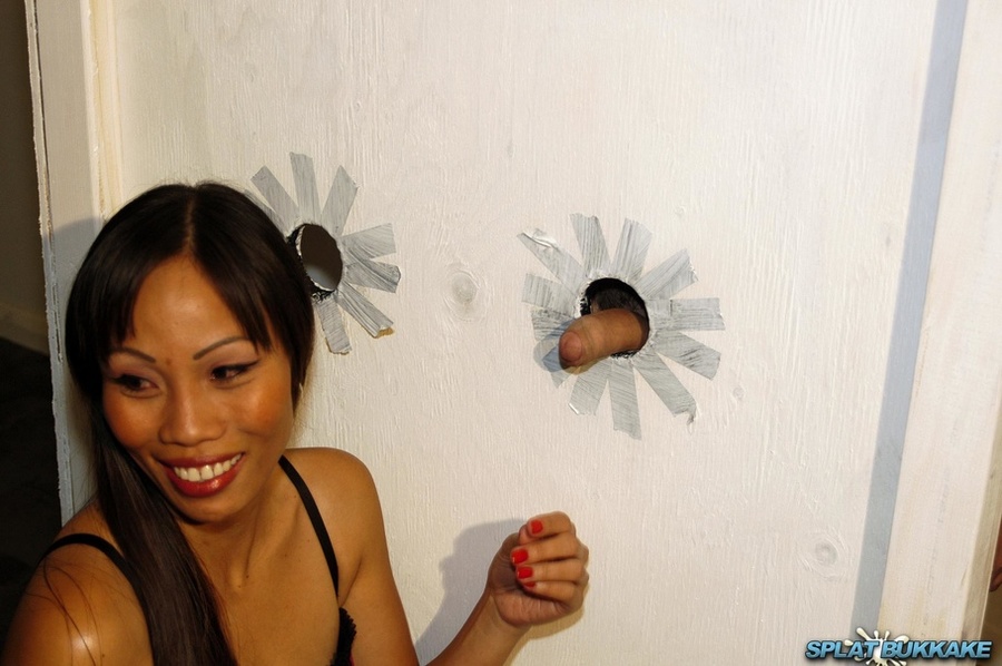 Asian hottie wearing black and pink lingerie sucking the juice out of two huge dicks peeking through the holes of a big white box and lets them spray cum on her mouth. - XXXonXXX - Pic 1