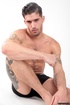 Two tattooed stallions with dark hair expose hard cocks and tight asses.