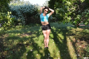 First-rate chica in a blue midriff shirt and black shorts flashing her boobs under a tree. - Picture 1