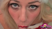 Gorgeous babe wearing her red and white santa hat and dress kneels down and blows a huge cock til it squirts on her nose.