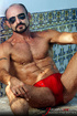 Muscular hung with a beard posing in red undershorts and showing his long