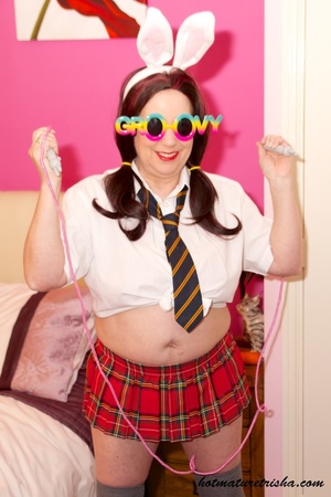 Mature chick in pigtails wearing school uniform strips off her white blouse and red skirt then expose her big body with large breasts wearing her black panty and shoes on a pink bed. - XXXonXXX - Pic 2