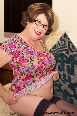 Mature chick with glasses strips off her colorful floral dress then pose her huge body in violet and black underwear, black stockings and purple high heels before she takes off her bra and expose her huge boobs on a brown couch. - XXXonXXX - Pic 10
