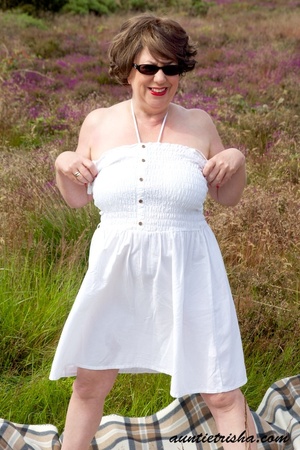 Gorgeous old babe with sunglasses wearing her all white dress and lingerie poses on a grassy field while slowly getting naked before she expose her huge boobs and nasty pussy. - XXXonXXX - Pic 3