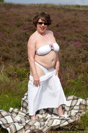 Gorgeous old babe with sunglasses wearing her all white dress and lingerie poses on a grassy field while slowly getting naked before she expose her huge boobs and nasty pussy. - XXXonXXX - Pic 6