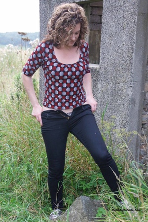 Gorgeous cougar in red and gray polka dotted shirt pulls down her blue jeans and white and black spotted panty and lets you peek at her hairy pussy outdoor. - XXXonXXX - Pic 4