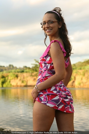 Delicious belle poses in a pink dress by the water and nude by a coconut tree. - Picture 1